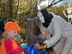 Seemingly unafraid, the brave pumpkin, also know as Ally Van Bakel (left), accepted the masked Garry Vivian's offer of candy during the Mitchell Optimist Club's annual Halloween Spooktacular held last Sunday, Oct. 25 at the Vorstenbosch farm just outside of Mitchell. GALEN SIMMONS/MITCHELL ADVOCATE