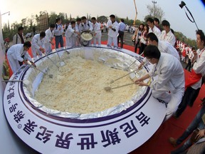 In this photo taken Thursday, Oct. 22, 2015, cooks stir more than 4 tons of fried rice in an attempt to break the Guinness Book of World Record for the largest serving of fried rice in Yangzhou in eastern China's Jiangsu province. (Chinatopix Via AP)