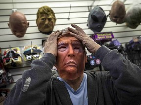 Employee Kenny Lomi adjusts a Halloween mask of Republican presidential candidate Donald Trump as he poses for a photo at the Village Party Store Halloween headquarters in the Manhattan borough of New York in this October 15, 2015 file photo. REUTERS/Andrew Kelly/Files