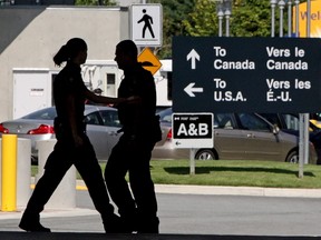 Canadian border guards are silhouetted as they replace each other at an inspection booth at the Douglas border crossing on the Canada-USA border in Surrey, B.C., in this Aug. 20, 2009 file photo. (THE CANADIAN PRESS/Darryl Dyck)