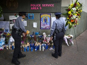 Police officers view a makeshift memorial for slain New York City Police (NYPD) officer Randolph Holder outside the Police Service Area 5 Precinct on East 123rd Street in the East Harlem neighborhood of Manhattan, in New York City, October 22, 2015. (REUTERS/Mike Segar)