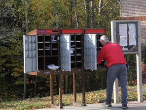 A Canada Post worker stuffs mail into community mailboxes in Barrie after reports national installation of such mailboxes will be put on hold until more consultations are held. PHOTO: CHERYL BROWNE