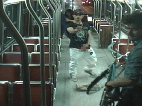 Sammy Yatim holds a knife and his exposed penis while TTC passenger Aaron Li-Hill moves away from him with his bike. (Screengrab)