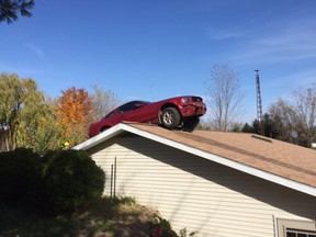 In this Oct. 26, 2015 photo, a Ford Mustang is stopped on a roof of a house in Woodhull Township, Mich. State police say the driver had a medical problem and lost control of his car on Interstate 69 in Shiawassee County. (Michigan State Police via AP)