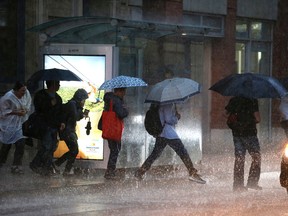 People run to jump on the Toronto streetcar in the pouring rain in this June 17, 2014 file photo. (Craig Robertson/Toronto Sun/Postmedia Network)
