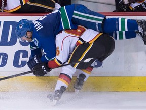 Vancouver Canucks defenceman Dan Hamhuis goes over Calgary Flames winger Turner Elson (65) as they fight for control of the puck during pre-season NHL action in Vancouver, B.C. Saturday, Sept. 26, 2015. (THE CANADIAN PRESS/Jonathan Hayward)
