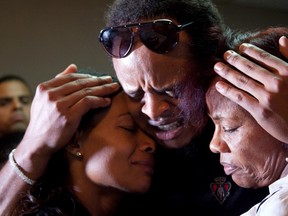 Kansas City Royals pitcher Edinson Volquez, centre, embraces his sister Wendy Volquez, left, and mother Ana Ramirez as they stand next to the body of his father Daniel Volquez at a funeral home in Santo Domingo Wednesday, Oct. 28, 2015. (AP Photo/Tatiana Fernandez)
