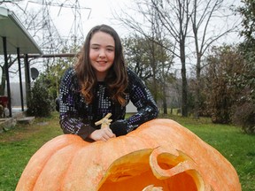 Ashley Hickey, 13, poses for a photo with her ribbon winning pumpkin, which she grew and which weighs 1,011 lbs, in Godfrey on Wednesday. (Julia McKay/The Whig-Standard)
