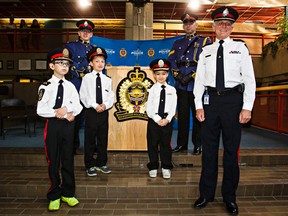 (From left) Edmonton "Police Chiefs for a Day" Atticus Paine, 10, Oaklin Litchfield, 9, and Lalla-Rita Hachim, 8, along with police chief Rod Knecht, far right, pose for a photo at the Edmonton Police Service Headquarters in Edmonton, Alta. on Tuesday, May 19, 2015. The children, all of whom have cancer, were selected to take part by the Kids With Cancer Society. Codie McLachlan/Edmonton Sun/Postmedia Network