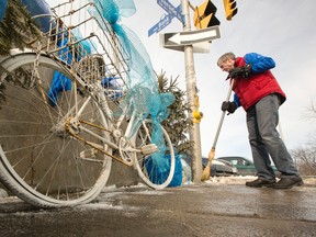 Paddy Dussault cleans the area by his wife, Meg Dussault's, ghost bike at the corner of Bank St. and Riverside Dr. Thursday March 05, 2015. Meg Dussault was struck and killed by a truck July 2013. (Postmedia Files)