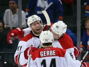 NEW YORK, NY - OCTOBER 29: Ron Hainsey #65 of the Carolina Hurricanes (r) celebrates his game winning goal at 2:21 of the overtime against the New York Islanders along with Jordan Staal #11 and Nathan Gerbe #14 at the Barclays Center on October 29, 2015 in the Brooklyn borough of New York City.   Bruce Bennett/Getty Images/AFP== FOR NEWSPAPERS, INTERNET, TELCOS & TELEVISION USE ONLY ==