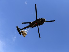 A helicopter carries remains of an adult Pentaceratops,Thursday, Oct. 29, 2015, in the Bisti-De-Na-Zin Wilderness area south of Farmington, N.M. The fossils are encapsulated in heavy plaster jackets. They're being trucked to the New Mexico Museum of Natural History and Science in Albuquerque. (Jon Austria/The Daily Times via AP)