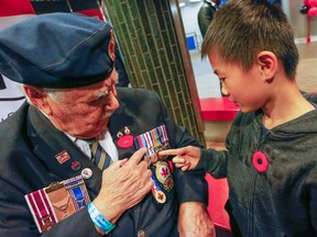Sheldon Lawr, 93, a Second World War vet, explains his war medals to 10-year-old Lorrin Shen at a poppy drive kick-off event at the Spadina subway station. (Dave Thomas/Toronto Sun/Postmedia Network)