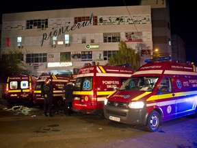 Ambulances are parked outside the site of an explosion that occurred in a club, housed by the building in the background, in Bucharest, early Saturday, Oct. 31, 2015. An explosion and ensuing flames on a stage at a Bucharest nightclub on Friday left more than 20 people dead and over 150 hospitalized with injuries, Romania's interior minister said. (AP Photo/Vadim Ghirda)