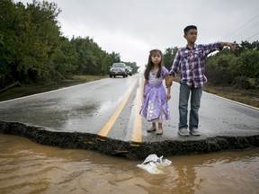 Miranda Chio, 4 and her brother Alex Chio, 10, look at York Creek where the road has washed away in Driftwood, Hays County, Texas October 30, 2015. High winds and heavy rains pelted central Texas on Friday, flooding highways, causing evacuations after rivers overflowed their banks and creating tornadoes that ripped through buildings outside San Antonio. More than 200 low-water crossings were closed due to the storm, which hit in the same area where flooding in late May caused more than 20 deaths. REUTERS/Ilana Panich-Linsman