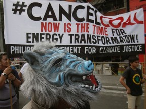 A protester, wearing a Halloween mask, stands near a protest banner during a rally near the Presidential Palace to protest the country's use of coal to power energy generation power plants which according to them has contributed to pollution Saturday, Oct. 10, 2015 in Manila, Philippines. The protesters are urging the Government to do more to reduce Greenhouse gas emissions which allegedly contributes to global climate change. (AP Photo/Bullit Marquez)