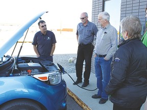 Ed Tanas, regional director of Sun Country Highway, speaks to Mayor Tom Grant, town councillor Paul Taylor, Vulcan Business Development Society (VBDS) administrative assistant Ashlee Beck, and VBDS manager of business development Marilyn MacArthur, about the features of his 2015 Kia Soul EV as it charges at the recently installed VBDS electric vehicle charging station.