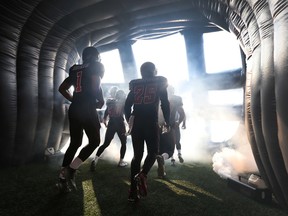 Ottawa RedBlacks players emerge from the giant helmet before a CFL game at TD Place. (Ottawa Sun files)