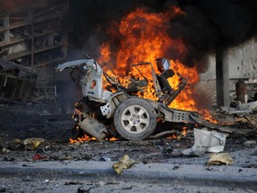 A burning car is seen on November 1, 2015 near the damaged Sahafi hotel in Mogadishu after an explosion. AFP PHOTO / MOHAMED ABDIWAHAB