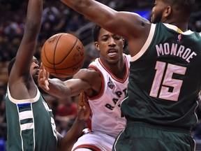 Toronto Raptors' DeMar DeRozan, centre, passes off the ball between Milwaukee Bucks' Kris Middleton, left, and Greg Monroe during first half NBA basketball action in Toronto, on Sunday, Nov. 1, 2015. THE CANADIAN PRESS/Frank Gunn