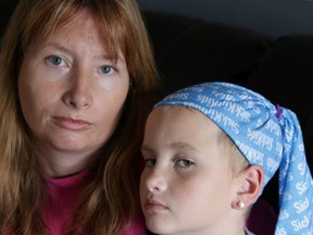 Tracy Vallier holds her daughter Alison, 8, at their house in Kingston on Monday. Vallier is waiting for employment insurance benefits to begin as she takes a leave from work to care for her daughter as she battles leukemia. (Elliot Ferguson/The Whig-Standard)