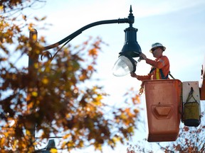 Ken Tilston, of Davies Electric, replaces a lightbulb in a streetlamp along University Drive in London. Tilston, working as part of a two man crew, replaced 21 burned out bulbs on the Western University campus on Monday using a lift on the back of his utility work truck.  (CRAIG GLOVER, The London Free Press)