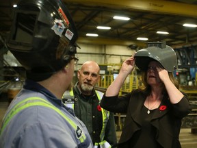 Lori Sigurdson, Minister of Jobs, Skills, Training puts on a welder's helmet before watching apprentice welder Dillian Doskoch do a practice weld at Supreme Group, Acheson Business Park in Spruce Grove, Alberta after announcing a new Job Creation Incentive Program, (TOM BRAID/Edmonton Sun)