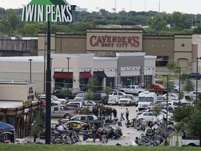In this May 17, 2015 file photo, authorities investigate a shooting in the parking lot of Twin Peaks restaurant in Waco, Texas. The family of a biker slain in a shootout outside the Waco restaurant has sued the restaurant's parent company alleging negligence, according to a lawsuit filed Wednesday, July 8, 2015, in Dallas County.  (AP Photo/Jerry Larson, File)