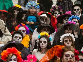 A girl in costume is held up during a Catrina Fest to commemorate Day of the Dead, a holiday that honors the deceased, in Mexico City, Sunday, Nov. 1, 2015. (AP/Esteban Felix)