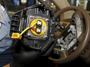 Technician Edward Bonilla holds a recalled Takata airbag inflator after he removed it from a Honda Pilot at the AutoNation Honda dealership service department in Miami, Florida June 25, 2015. The yellow circular device is the airbag inflator.  REUTERS/Joe Skipper