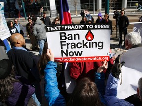 In this Tuesday, Feb. 24, 2015 file photo, an activist waves a placard calling for the ban of fracking during a news conference outside the Colorado Convention Center in Denver. (AP Photo/David Zalubowski, file)