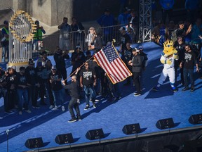 Kansas City Royals' Jonny Gomes runs across the stage with a flag during during the rally to celebrate the Royals winning baseball's World Series Tuesday, Nov. 3, 2015, in Kansas City, Mo. (AP Photo/Reed Hoffmann)
