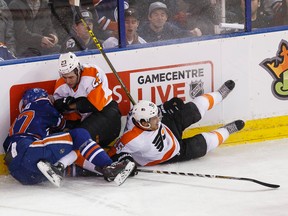 Edmonton centre Connor McDavid (97) crashes into the boards with Philadelphia defenceman Brandon Manning (23) and defenceman Michael Del Zotto (15) during the second period of a NHL game between the Edmonton Oilers and the Philadelphia Flyers at Rexall Place in Edmonton, Alta. on Tuesday November 3, 2015. McDavid held his shoulder after the hit. Ian Kucerak/Edmonton Sun/Postmedia Network