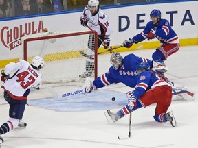 New York Rangers goalie Henrik Lundqvist (30), of Sweden stops a shot by Washington Capitals' Tom Wilson (43) as teammates Marc Staal (18) and Kevin Klein (8) watch during the third period of an NHL hockey game Tuesday, Nov. 3, 2015, in New York. The Rangers won 5-2. (AP Photo/Frank Franklin II)