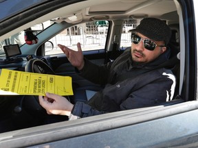 UberX driver Mohamed holds a mock ticket educating handed out by Beck Taxi on Nov. 4, 2015. (Craig Robertson/Toronto Sun)