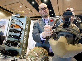 Ted Shuter, product manager for Revision Electronics and Power Systems Inc., attaches a polycarbonate visor to a polyethylene ballistic helmet at the Montreal-based company?s booth at the Best Defence Conference at the London Convention Centre Wednesday. The helmet can be fitted with a face protector capable of stopping a small munitions round. (CRAIG GLOVER, The London Free Press)