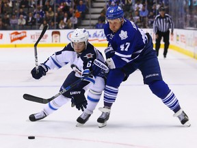 Maple Leafs forward Leo Komarov (right) gets held up by Jets forward Alex Burmistrov during NHL action at the Air Canada Centre in Toronto on Wednesday, Nov. 4, 2015. (Dave Abel/Toronto Sun)