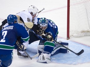 Canucks defenceman Dan Hamhuis (left) looks on as Penguins captain Sidney Crosby (centre) puts a shot past Canucks goalie Ryan Miller during third period NHL action in Vancouver on Wednesday, Nov. 4, 2015. (Jonathan Hayward/THE CANADIAN PRESS)