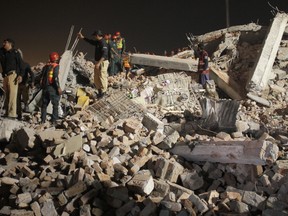 Pakistani volunteers and police officers take part in rescue work following the collapse of a building in Lahore, Pakistan, Wednesday, Nov. 4, 2015. The factory building under construction in an industrial area on the outskirts of Pakistan's eastern city of Lahore collapsed on Wednesday, killing many workers and injuring dozens, officials said. (AP Photo/K.M. Chaudary)