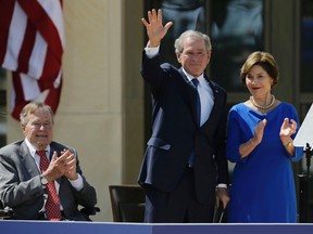 In this April 25, 2013, file photo, Former President George H.W. Bush, left, applauds with Laura Bush after former President George W. Bush's speech during the dedication of the George W. Bush Presidential Center in Dallas. Former President George H.W. Bush is publicly criticizing for the first time key members of his son's administration. A biography of the nation's 41st president to be published in November, 2015, contains his sharply critical assessments of former Vice President Dick Cheney and Defense Secretary Donald Rumsfeld. (AP Photo/David J. Phillip, File)