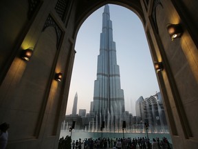 In this Monday, April 13, 2015, with the world tallest tower, Burj Khalifa, in the background, tourists and visitors watch and take photos of the Dubai Fountain in Dubai, United Arab Emirates. (AP Photo/Kamran Jebreili, File)