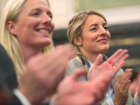 Minister of Environment and Climate Change Catherine McKenna, left, applauds beside Minister of Canadian Heritage Melanie Joly as they take part in a Liberal caucus meeting on Parliament Hill in Ottawa on Thursday, November 5, 2015. THE CANADIAN PRESS/Sean Kilpatrick