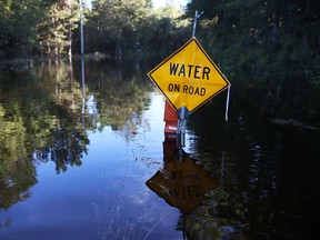 A water on road sign is seen next to a flooded road as water that breached dams upstream reach areas in the eastern part of the state on October 8, 2015 in Givhans South Carolina. The state of South Carolina experienced record rainfall amounts over the weekend and officials expect the damage from the flooding waters to be in the billions of dollars.  Joe Raedle/Getty Images/AFP