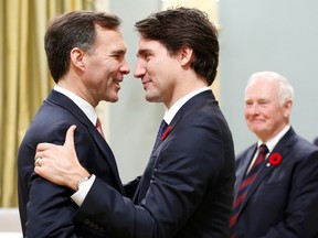 Finance Minister Bill Morneau (L) is congratulated by Prime Minister Justin Trudeau as Governor General David Johnston (R) watches at Rideau Hall in Ottawa November 4, 2015.   REUTERS/Chris Wattie