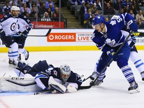 Byron Froese of the Toronto Maple Leafs digs for the puck on Ondrej Pavelec of the Winnipeg Jets during NHL action at the Air Canada Centre in Toronto on Nov. 4, 2015. 9Dave Abel/Toronto Sun/Postmedia Network)
