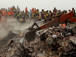 Excavators dig rubble of a collapsed building looking for survivors in Lahore, Pakistan, Friday, Nov. 6, 2015. Officials say a teenager was rescued on Friday after 50 hours trapped under the rubble of a four-story factory which collapsed this week in eastern Pakistan. (AP Photo/K.M. Chaudary)