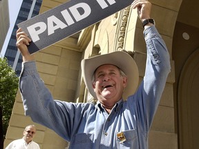 Alberta's Premier Ralph Klein holds a sign, July  12, 2004, saying "Paid In Full" after announcing that Alberta's debt would be completely paid off that year. (CALGARY SUN FILE)
