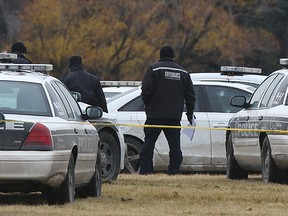 A Winnipeg Police forensics services officer examines a bullet-ridden white Audi A4 in Lipsett Hall field near the corner of Grant Avenue and Kenaston Boulevard in Winnipeg on Fri., Nov. 6, 2015. A man was taken to hospital with undetermined injuries after an officer-involved shooting. Kevin King/Winnipeg Sun/Postmedia Network