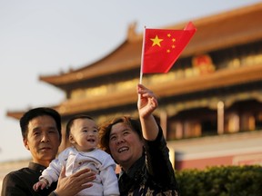 Guan Junze (C) and his grandparents take their souvenir picture in front of the Tiananmen Gate in Beijing November 2, 2015. China must continue to enforce its one-child policy until new rules allowing all couples to have two children go into effect, the top family planning body said. The ruling Communist Party said last week that Beijing would loosen its decades-old one-child policy. The plan for the change must be approved by the rubber-stamp parliament during its annual session in March.  REUTERS/Kim Kyung-Hoon