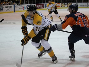 Sarnia Sting centre Daniel Nikandrov fires a shot despite being held back by the stick of Flint Firebirds pivot Ryan Moore during the Ontario Hockey League game at the Sarnia Sports and Entertainment Centre Friday night. Moore scored the overtime winner for a 3-2 Firebirds' victory. (Terry Bridge, Sarnia Observer)